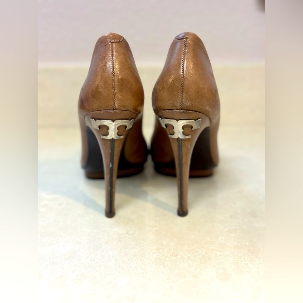 Tory Burch closed toe pumps with metal decal on heel.